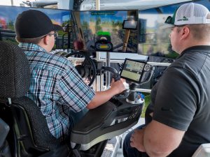 Two people driving tractor with multiple monitors